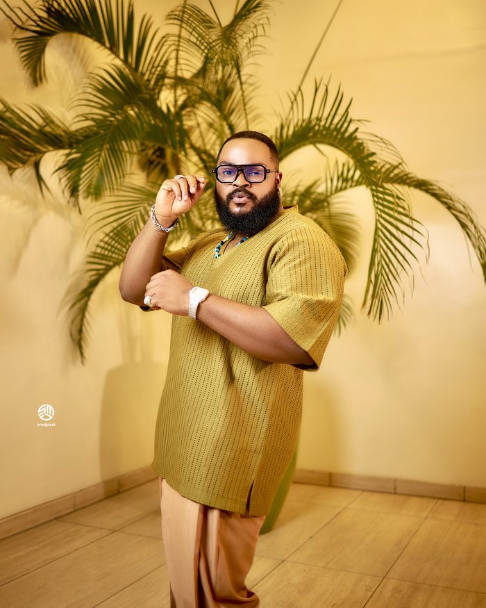 Whitemoney adjusting his glasses in an olive knit set